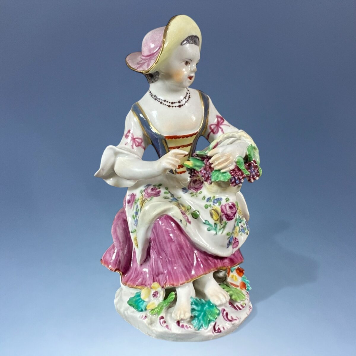 C18th Bow Figure of a Girl Holding a Basket of Grapes.