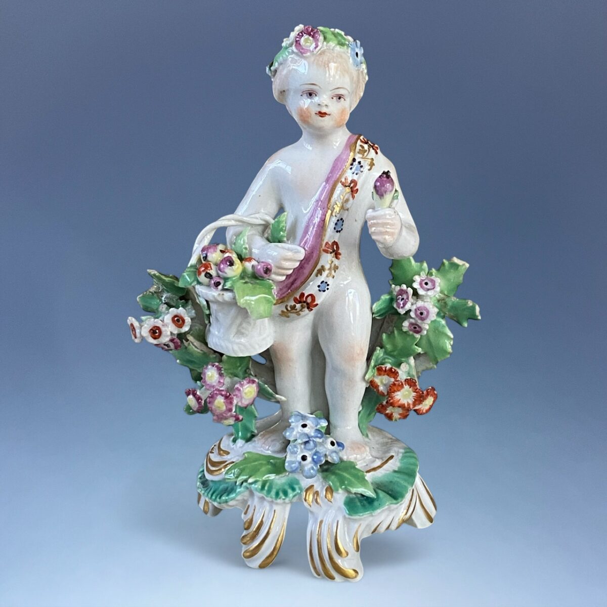 C18th BOW Porcelain – Small Figure of a Putto With Basket of Fruit.